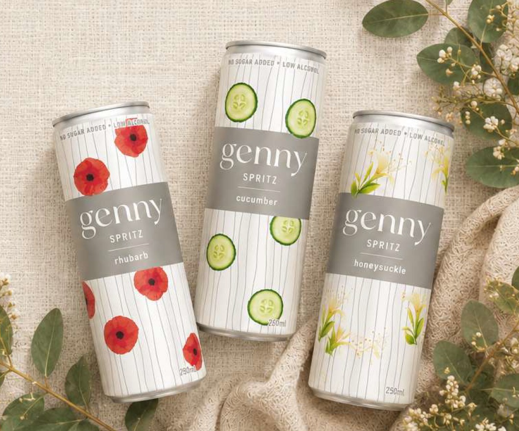 Three cans of genny spritz — honeysuckle, cucumber and rhubarb — resting on linen with eucalyptus and baby's breath.
